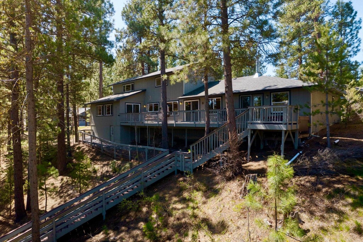 Sprawling window-filled rear of home with elaborate stair system to the river below.