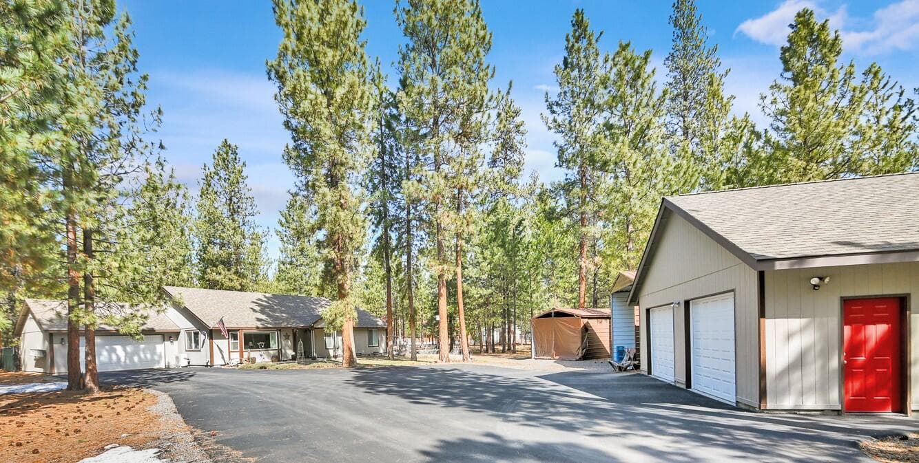 Paved driveway entrance to the property with plenty of room to maneuver an RV. Shop is on the right with home set back on the property.