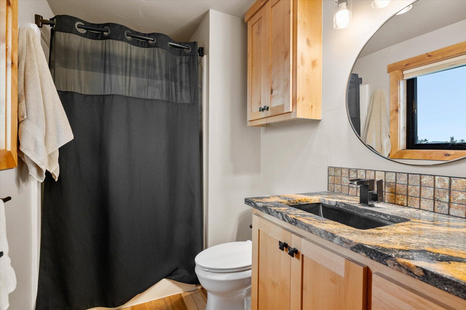 Full bath with tiled backsplash and oval mirror.