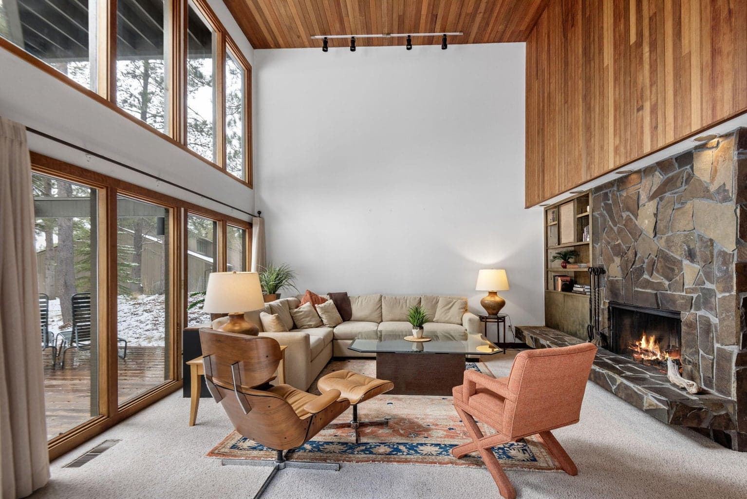 Living room with huge floor to ceiling windows to vaulted wood celings and real wood stone fireplace.