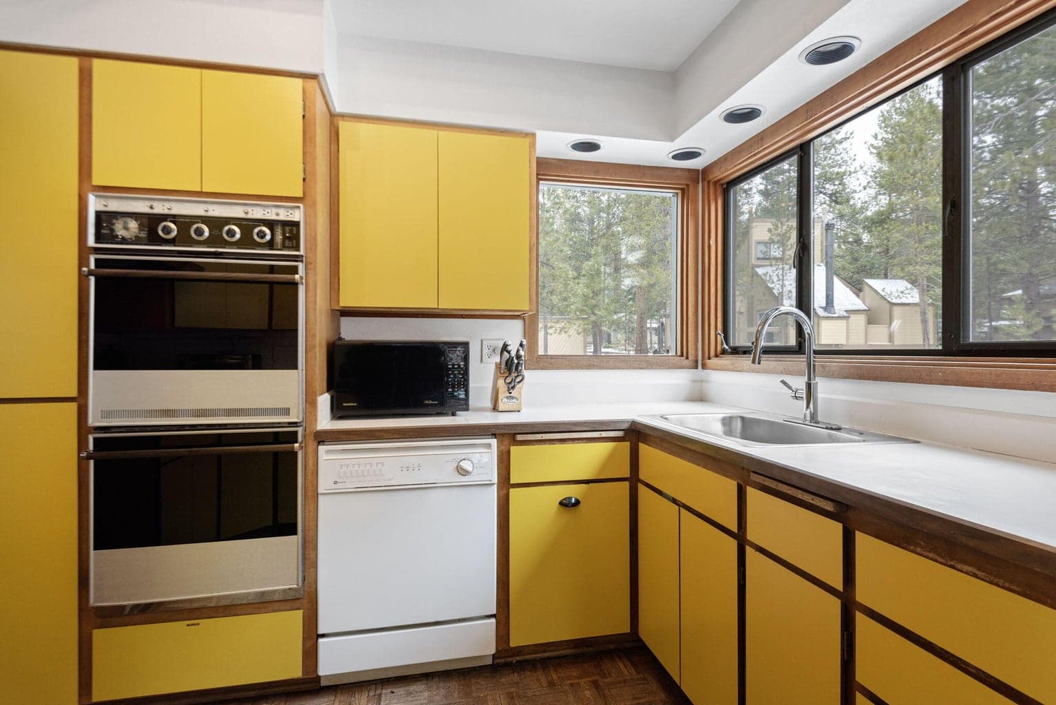 Double oven and kitchen looking out to trees and the golf course.
