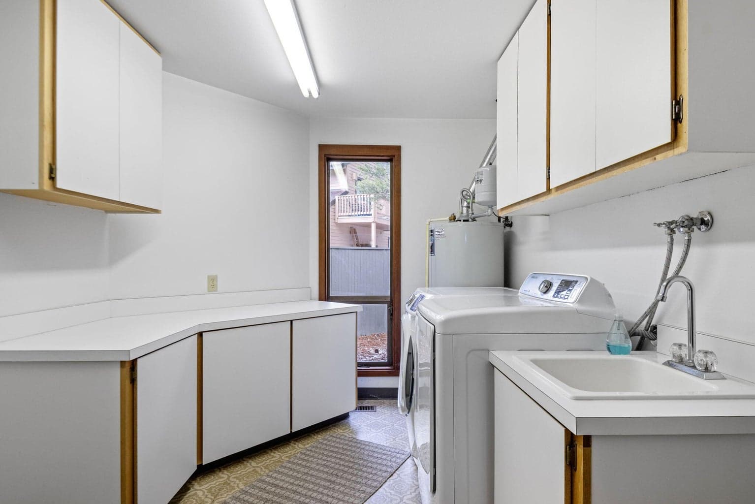 Downstairs laundry roo with lots of storage and cabinets and sink.