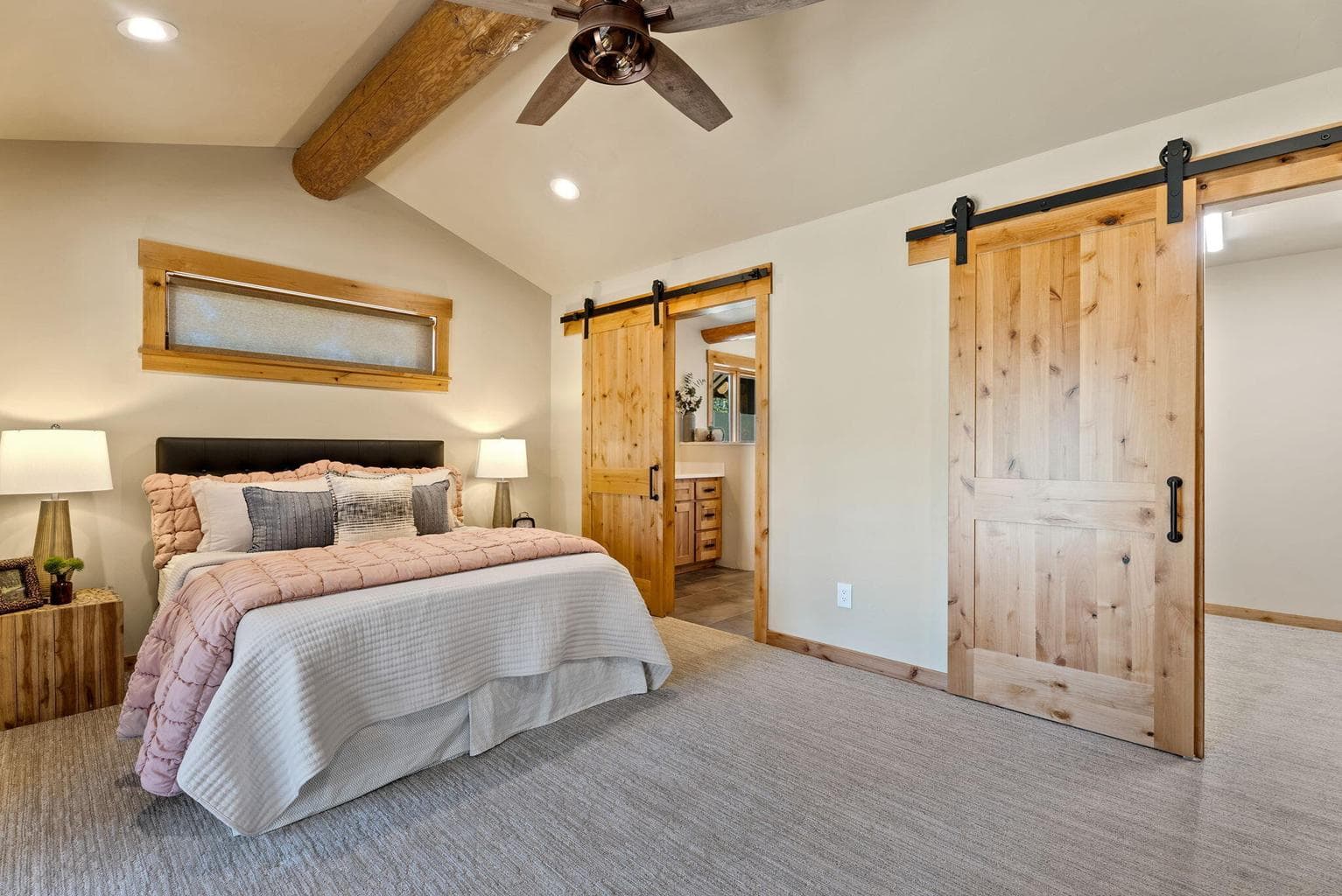 Primary ensuite features vaulted, log-beam ceiling, large walk-in closet, and outdoor living area.