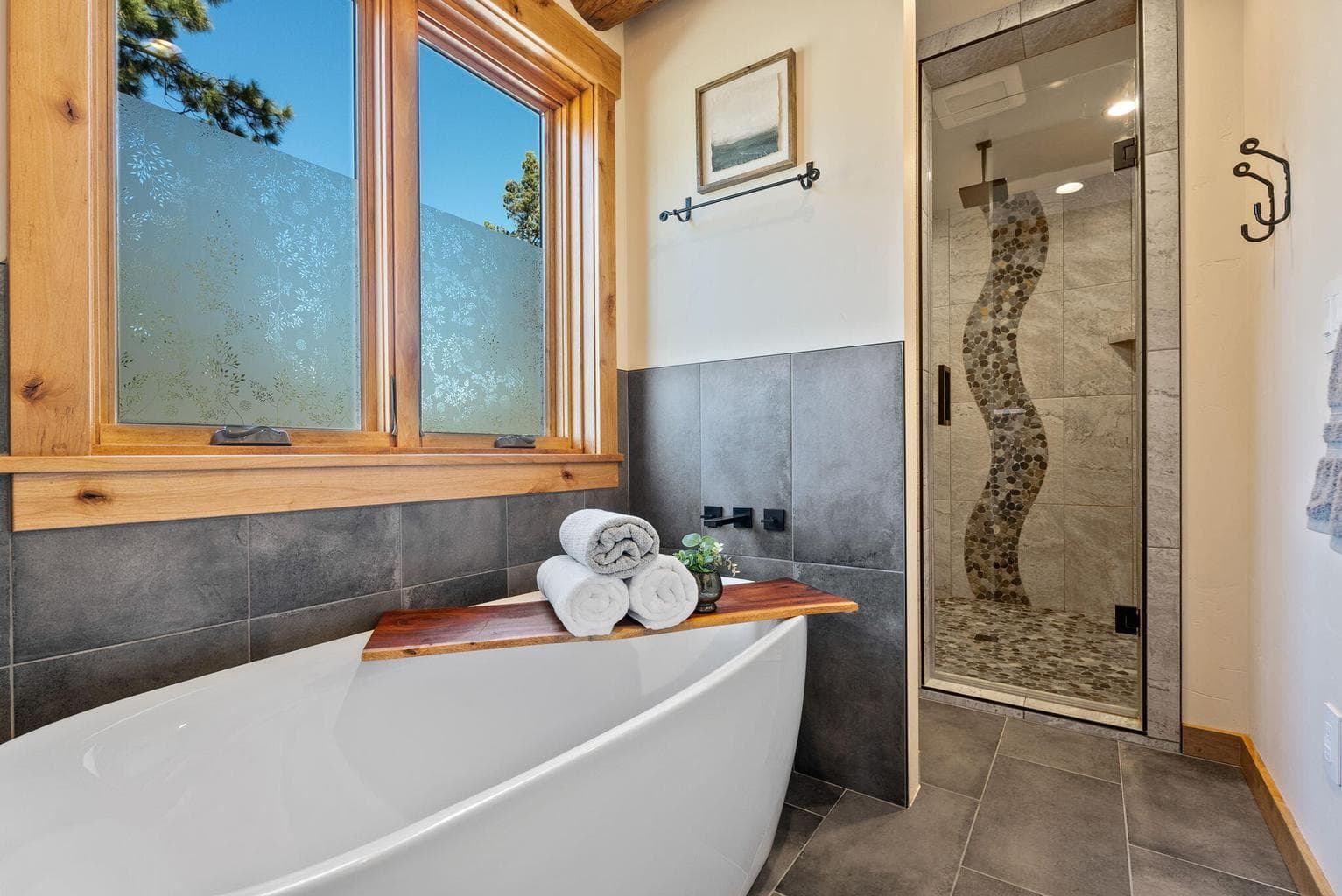 Primary soaking tub and glass, walk-in tiled shower with unique tile design.