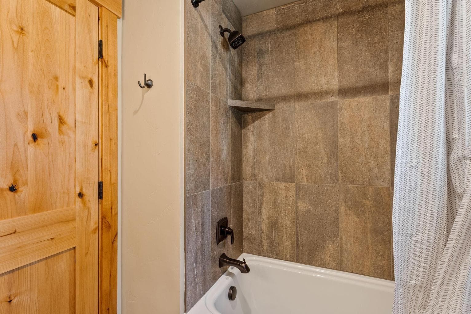 Guest bath features tiled flooring, tiled shower surround, and a single vanity with copper sink.