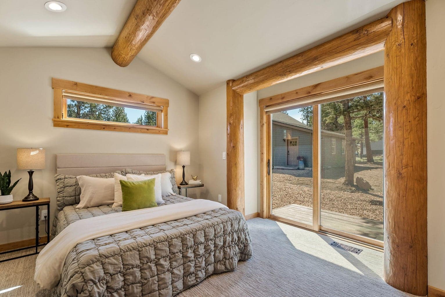 Guest bedroom features vaulted, log-beam ceiling, large closet with built-ins, and private outdoor seating area.