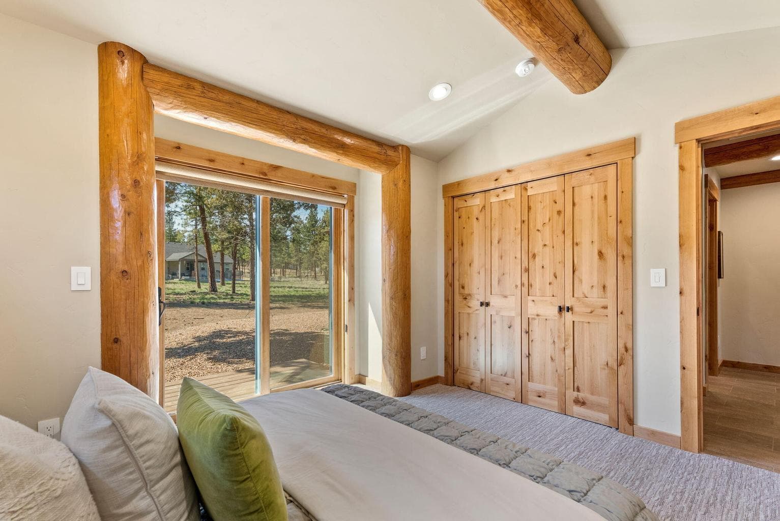 Guest bedroom features vaulted, log-beam ceiling, large closet with built-ins, and private outdoor seating area.