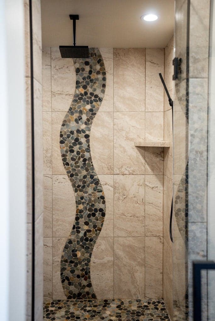 Primary soaking tub and glass, walk-in tiled shower with unique tile design.