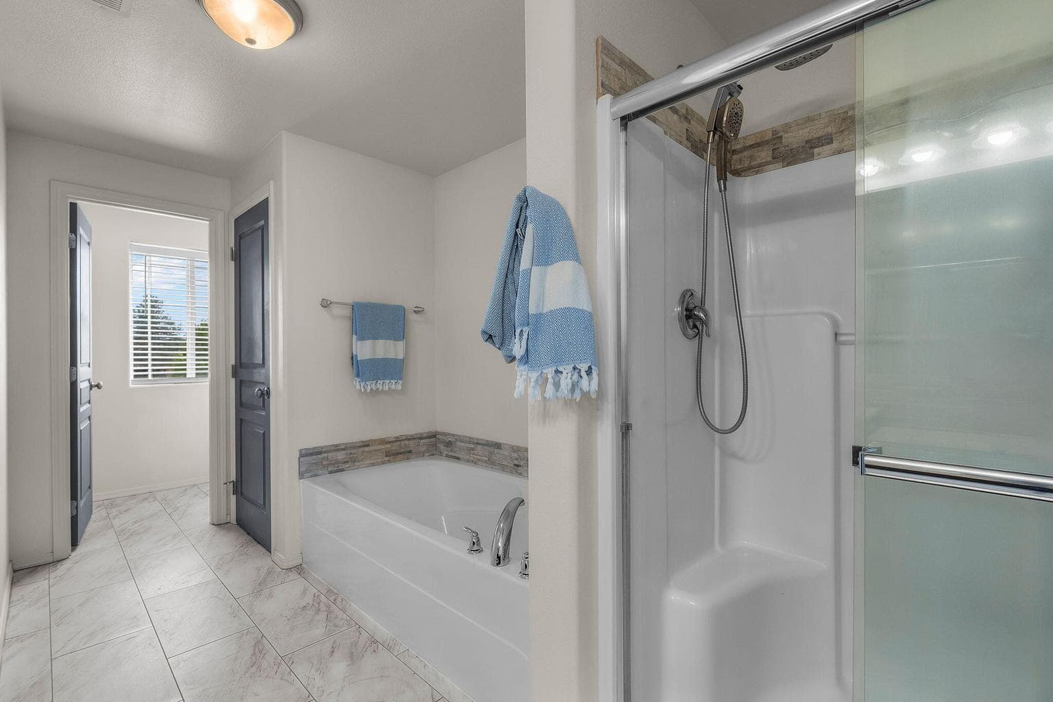 Spacious primary bathroom with tub and separate shower and enclosed toilet