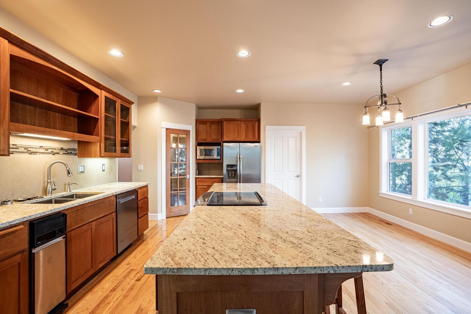 Kitchen boasts granite tops, large island, wood cabinets, stainless appliances, and full height backsplash