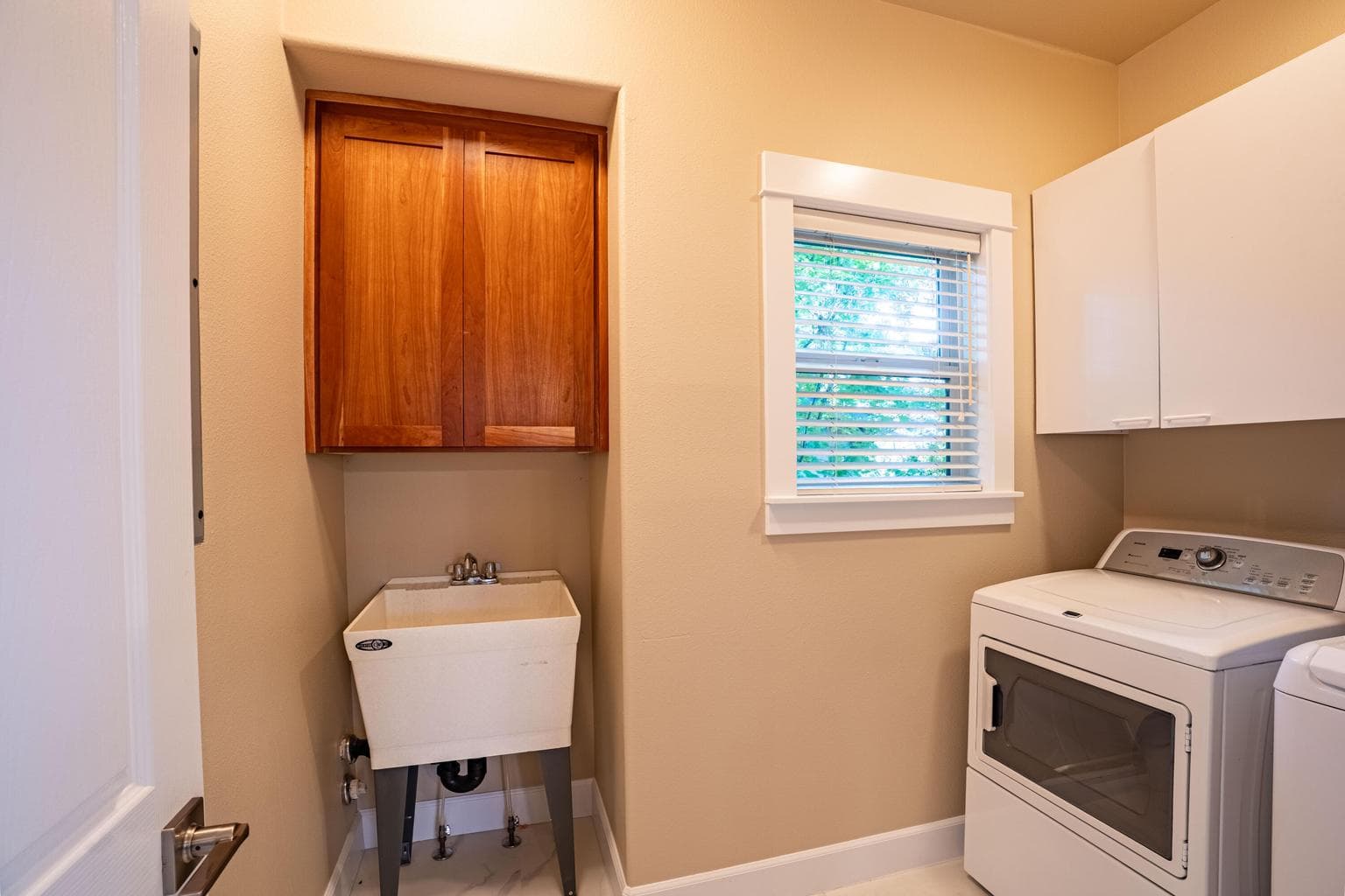 Laundry room has updated flooring, upper cabinets and deep basin utility sink. Washer Dryer included