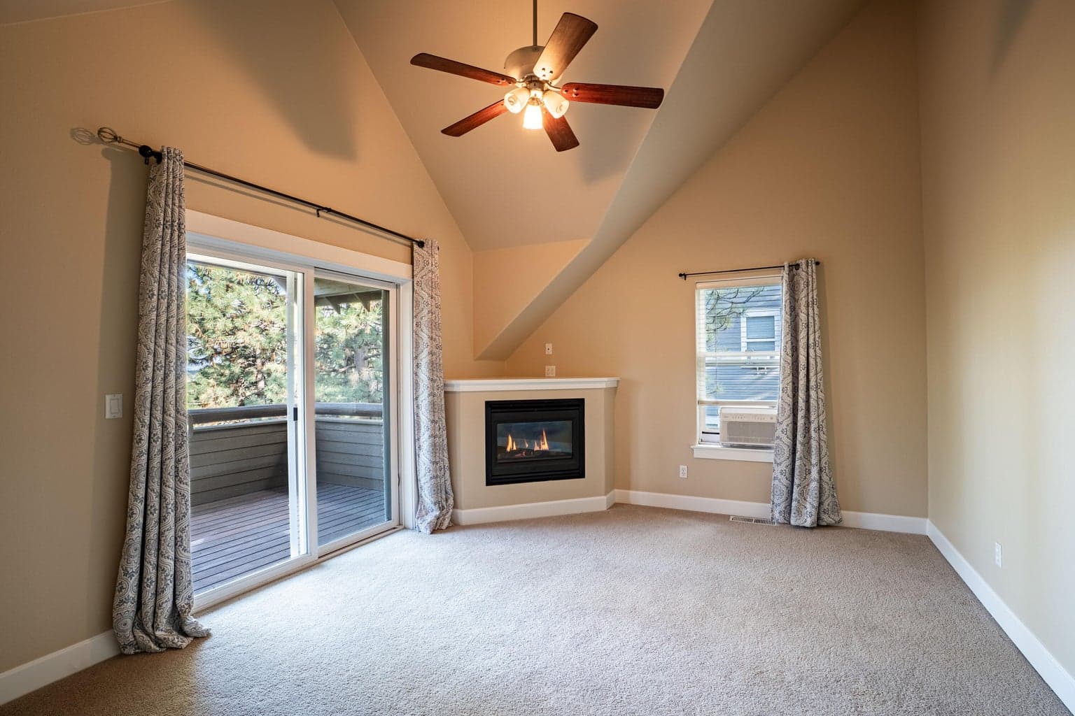 Primary suite offers vaulted ceilings, ceiling fan, corner gas fireplace and a private balcony