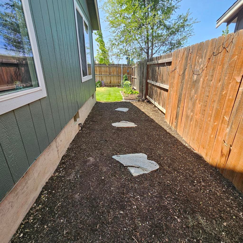 Mulch area with stepping stones from the patio to the Back yard.