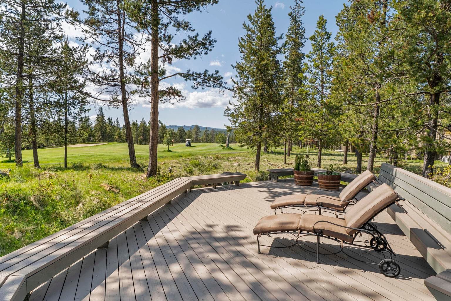 Peaceful outdoor deck with built-in bench seating, all set against a scenic backdrop golf course and distant mountain views.