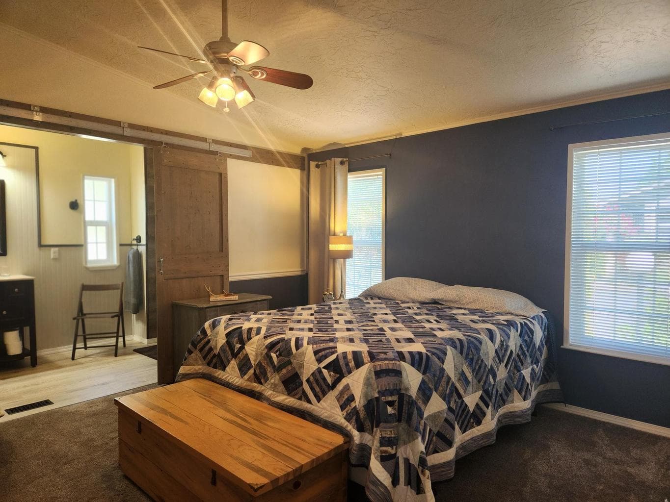 Primary suite has new carpet, accent wall, ceiling fan and barn door.