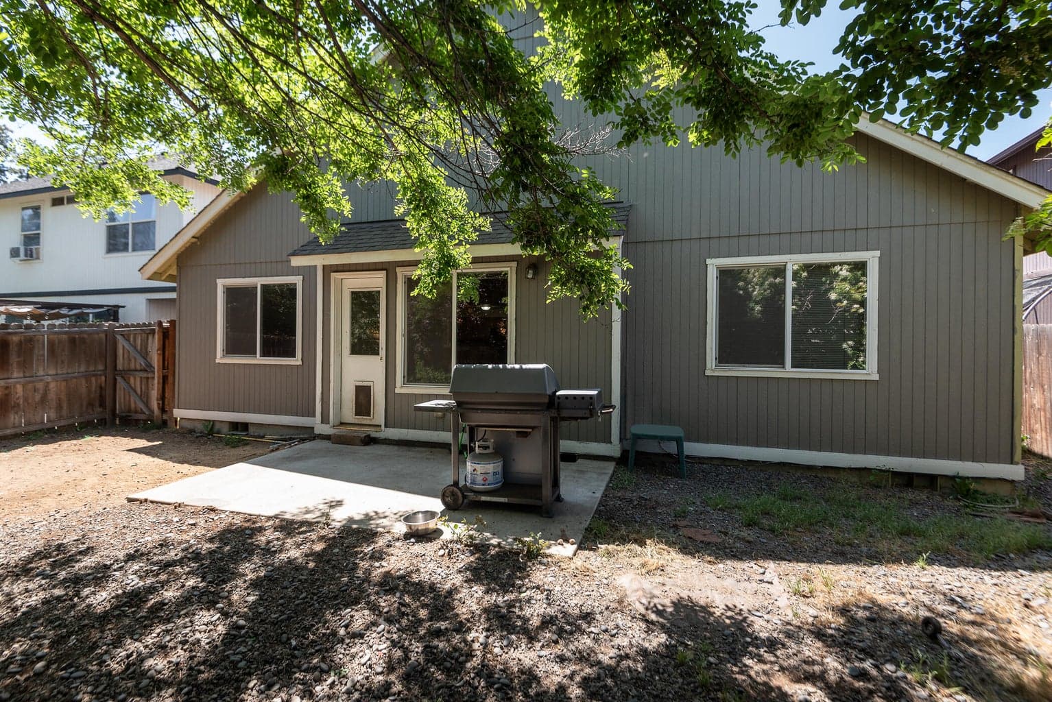 Level and fenced backyard space with mature trees and patio.