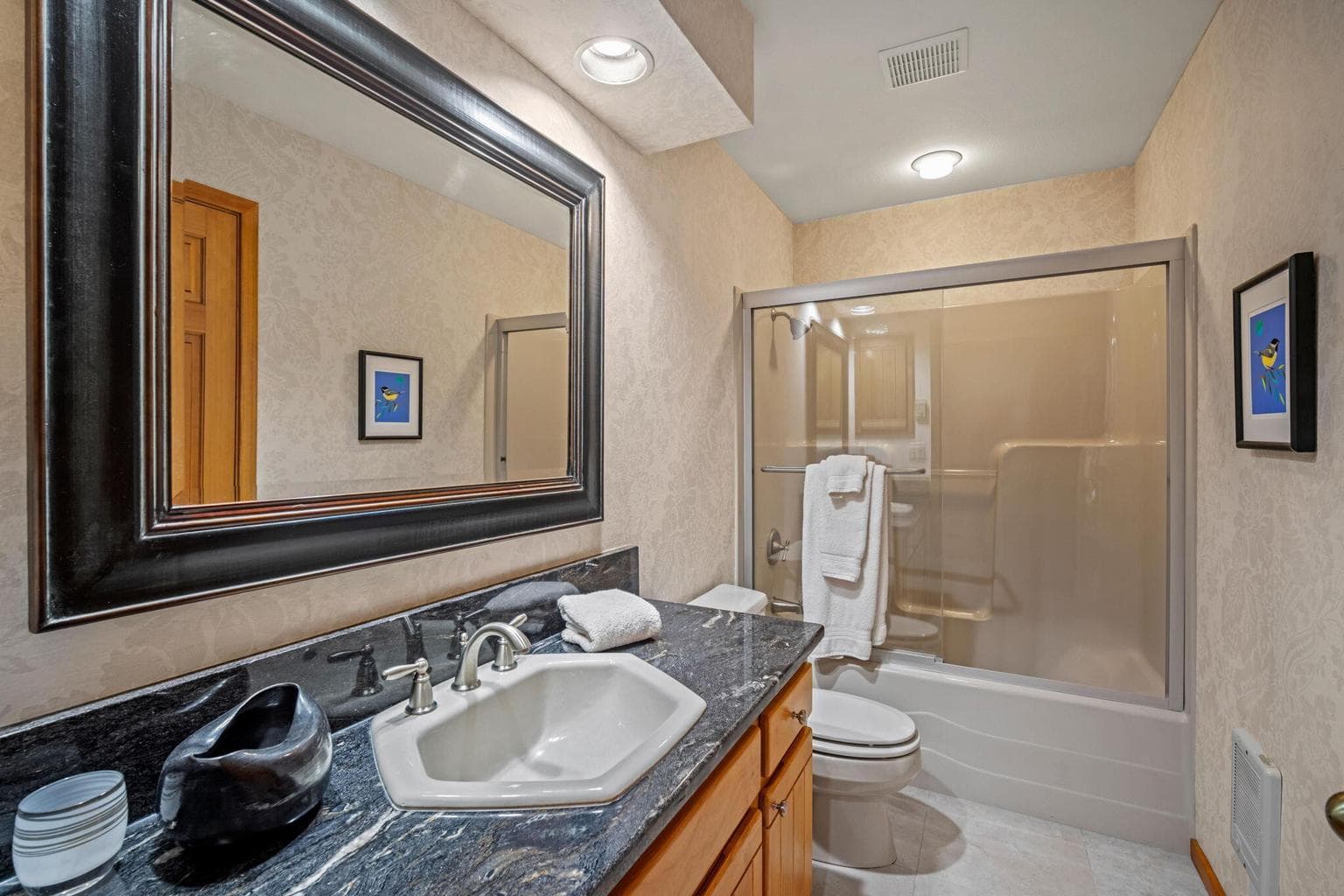 One of 2 full bathrooms located on the main level, featuring a shower/tub combo and a granite counter top.