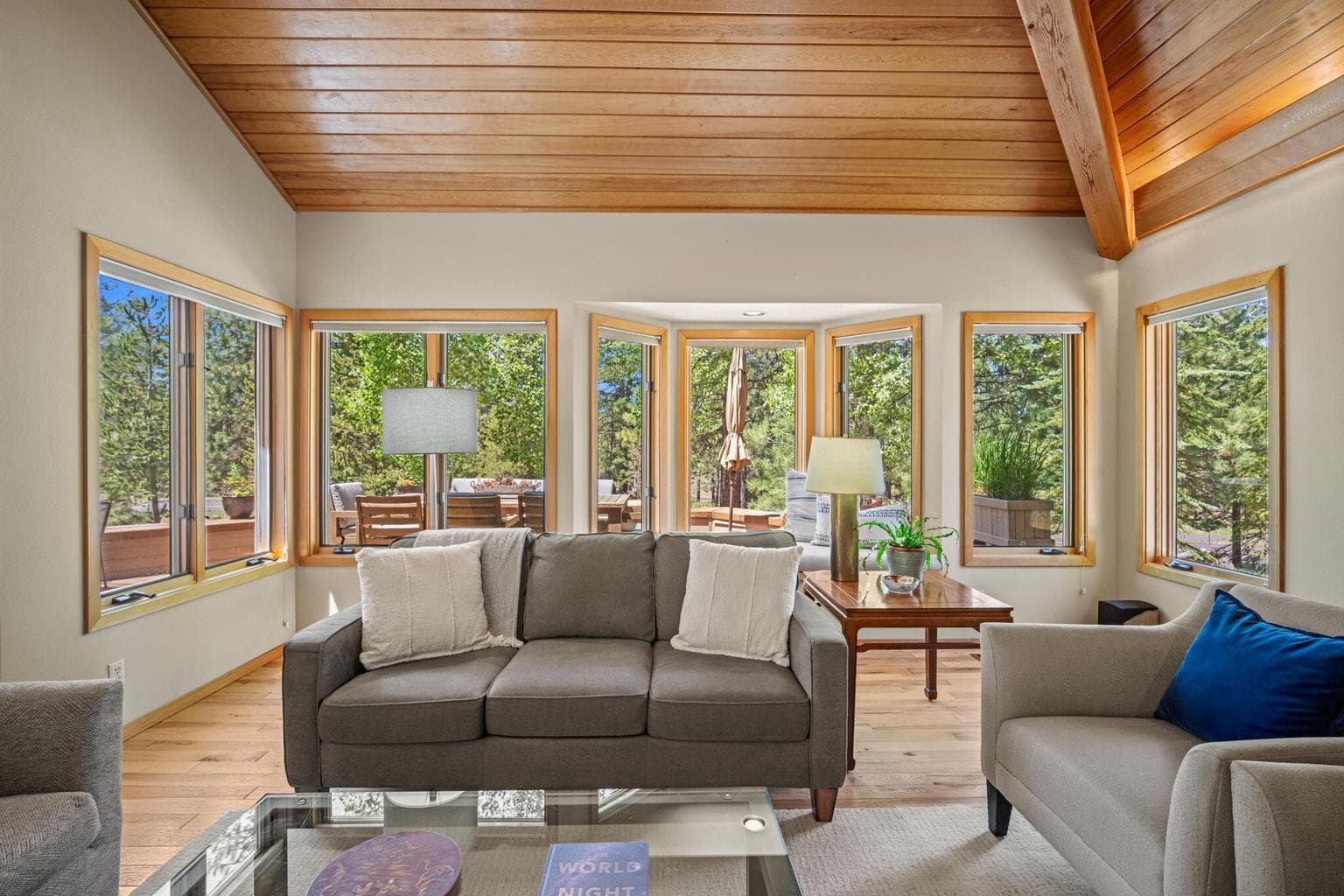 Comfortable living room area within the great room, enjoys a panoramic view from a wall of windows and clear cedar ceilings.