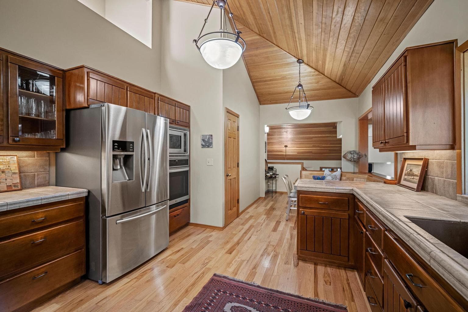 View from within the kitchen towards the banquette. Lots of counterspace and warm, wood toned cabinets.