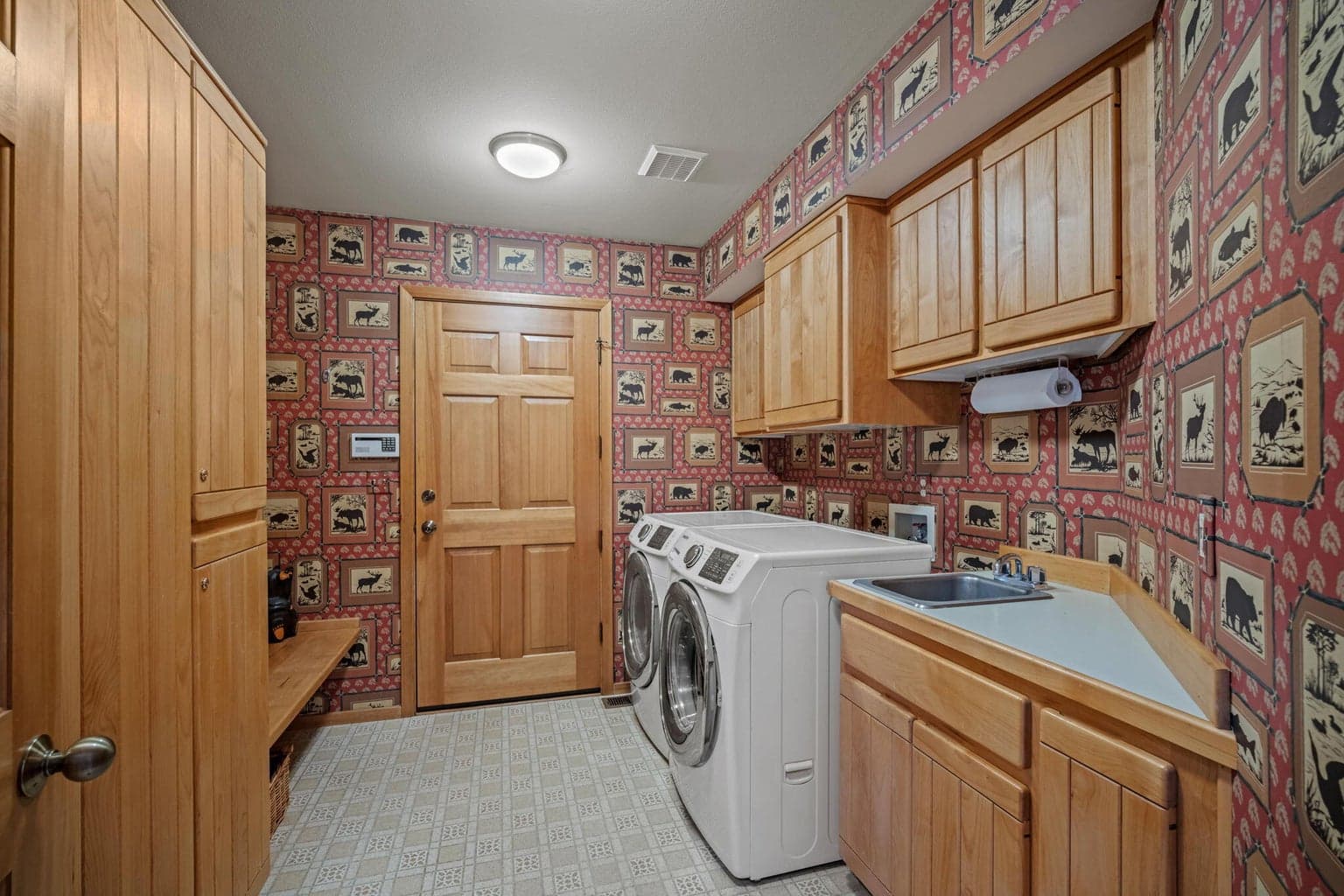 Laundry room with built in storage, built in bench, counter, sink and lots of storage.