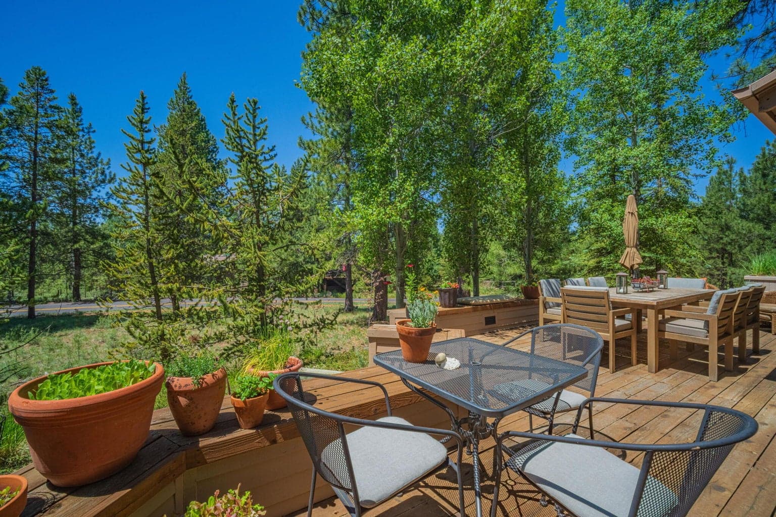 Expansive back deck with lots of room for many seating areas, featured in the foreground a wrought iron table, perfect for your morning coffee.