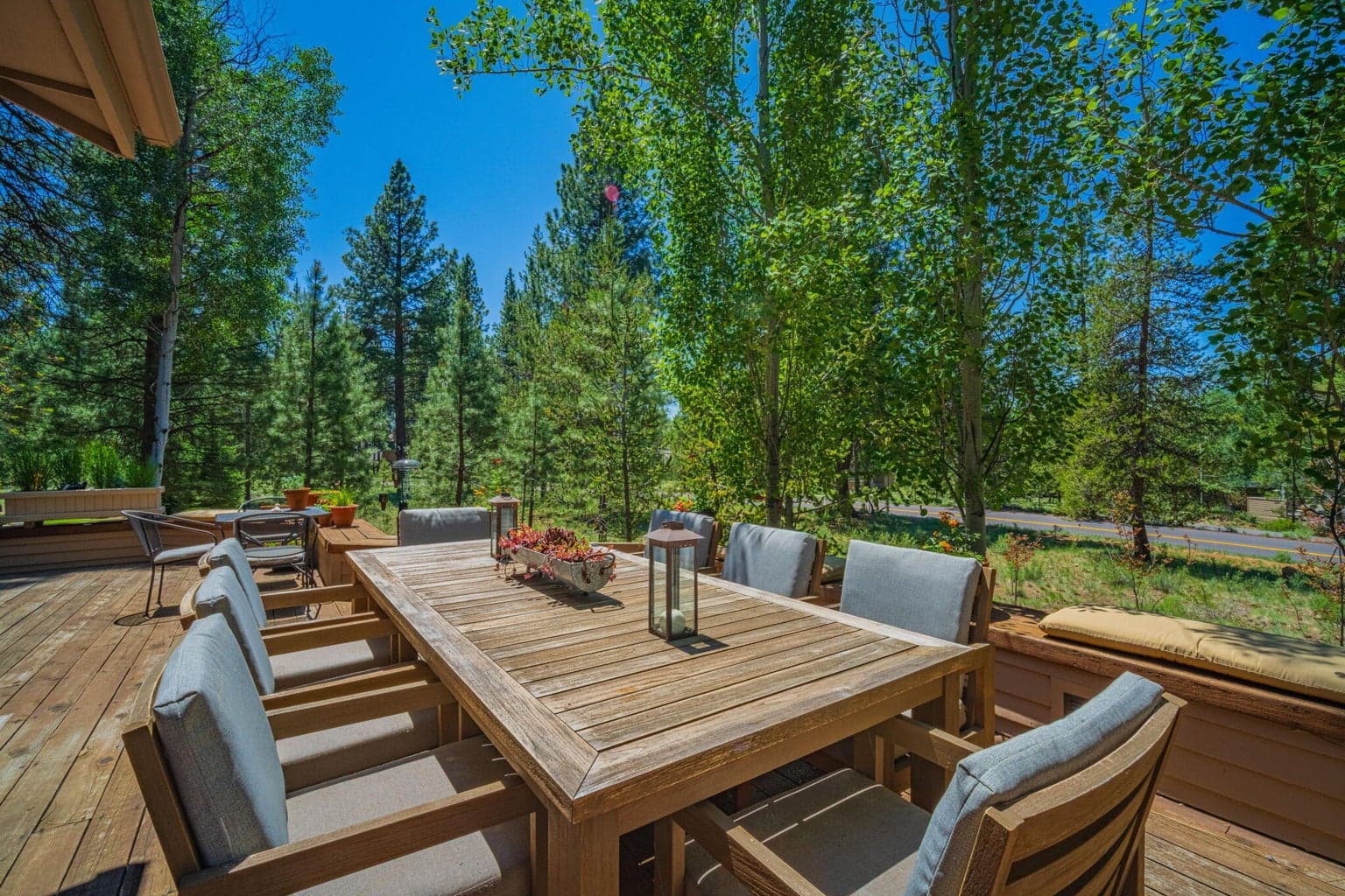 A view into the trees from the back deck with space for this giant table that seats 8 and surround, built-in seating.