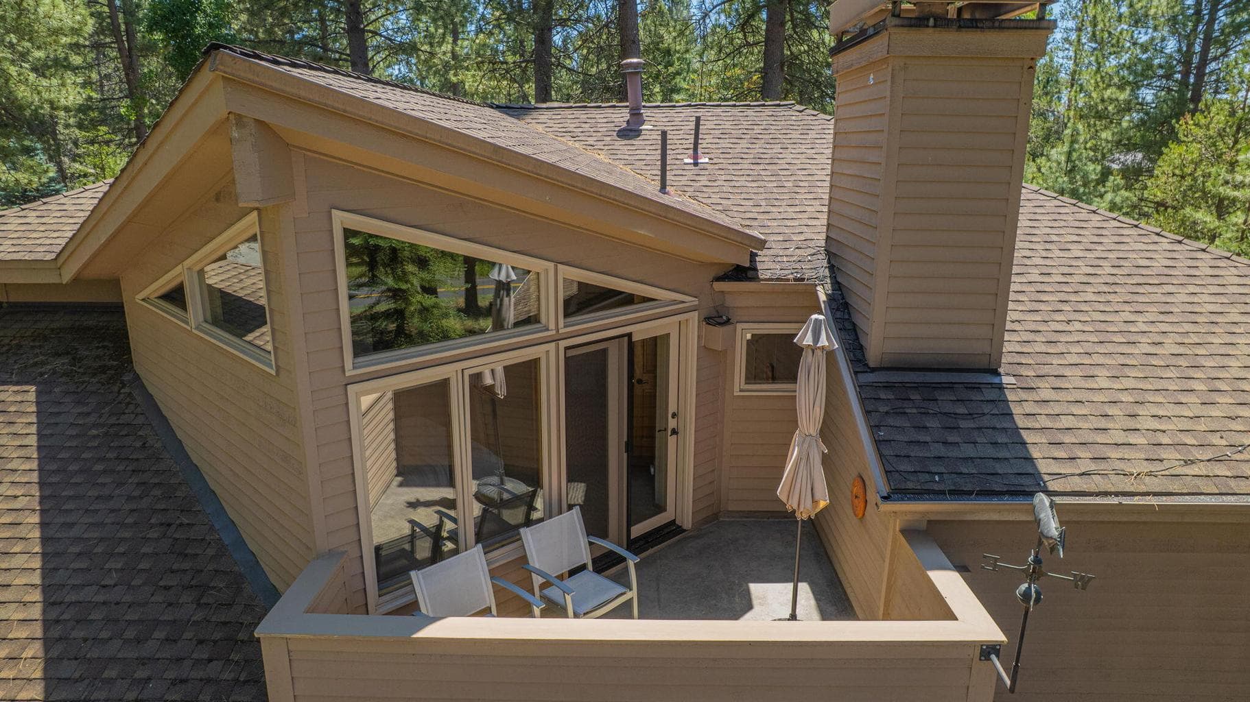 Aerial, birds eye view of the many custom angles characteristic of this home - featured here, the private primary suite sun deck.