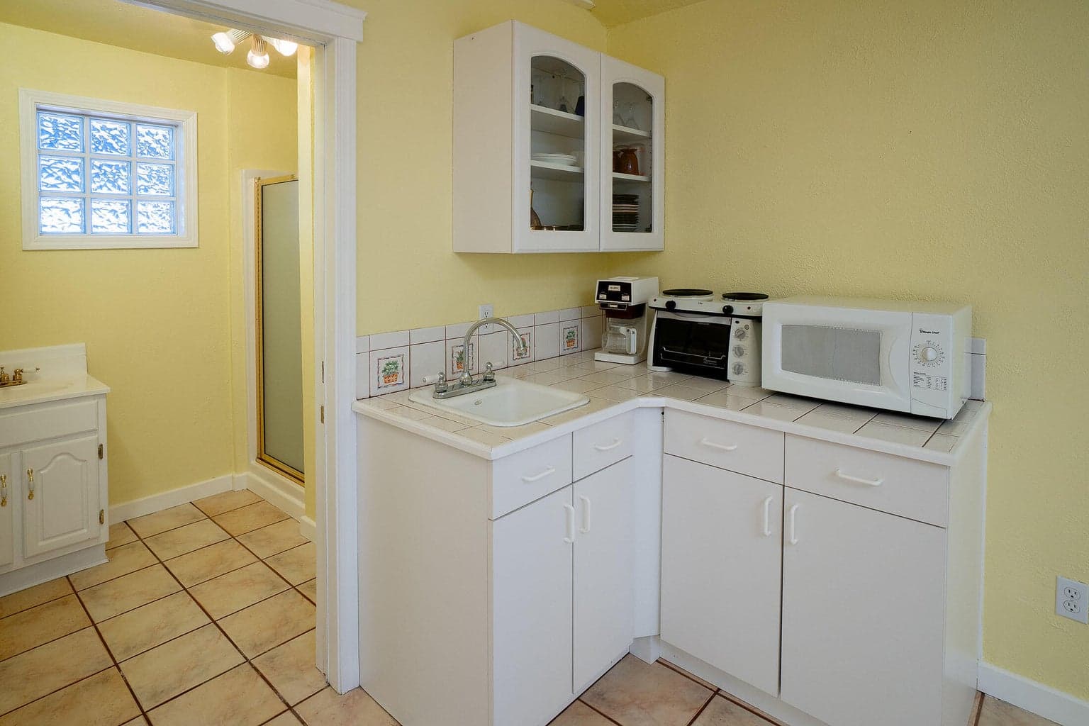 A glimpse of the convenience area in the guest cottage, with sink, upper & lower cabinetry, microwave.