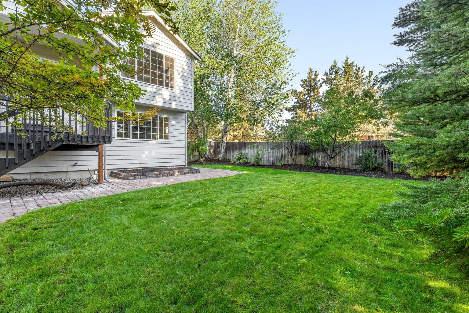 Mature evergreens and other trees provide beauty and privacy in front.