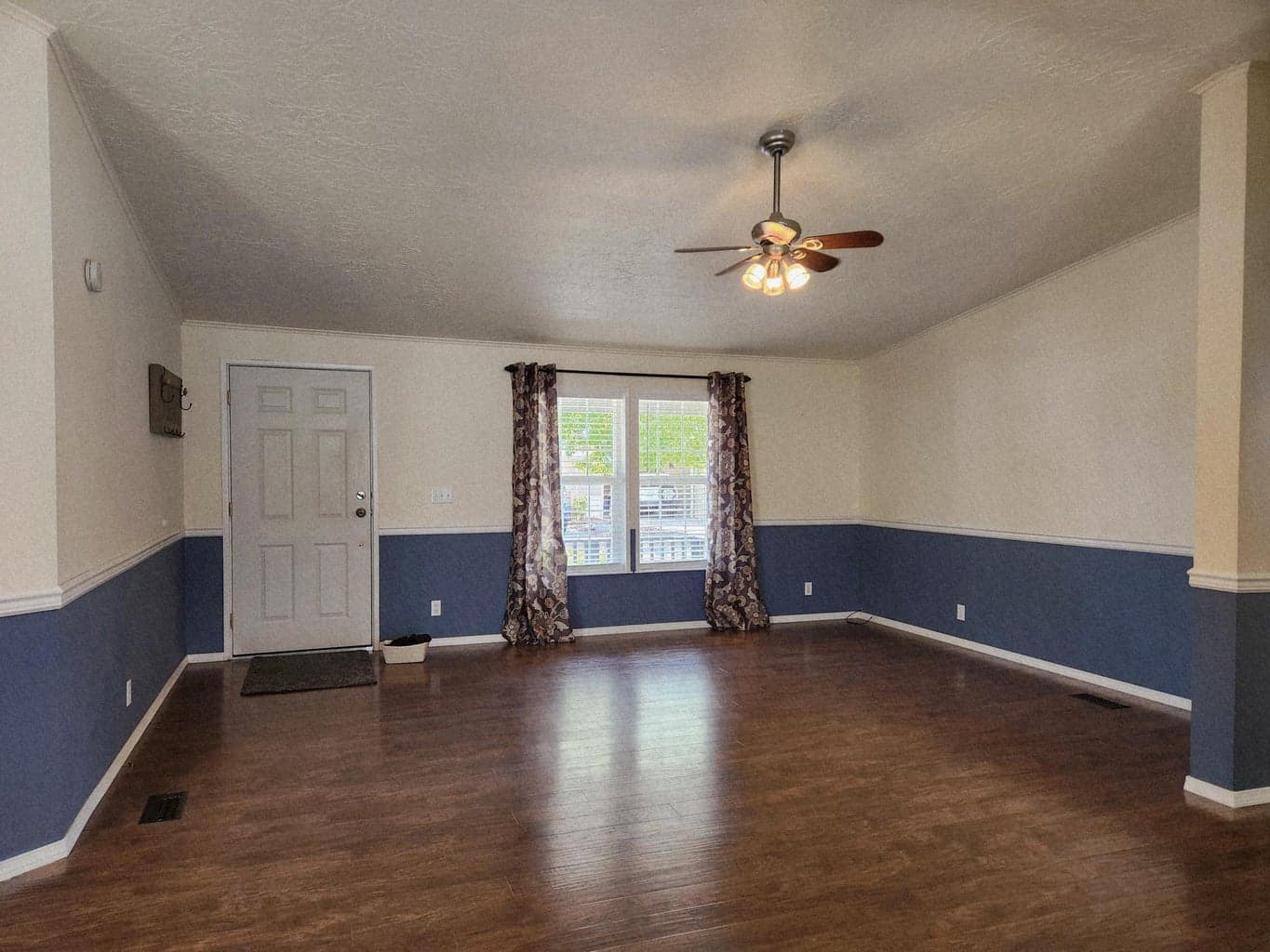 Living room has lots of light, vaulted ceilings, laminate floors and ceiling fan