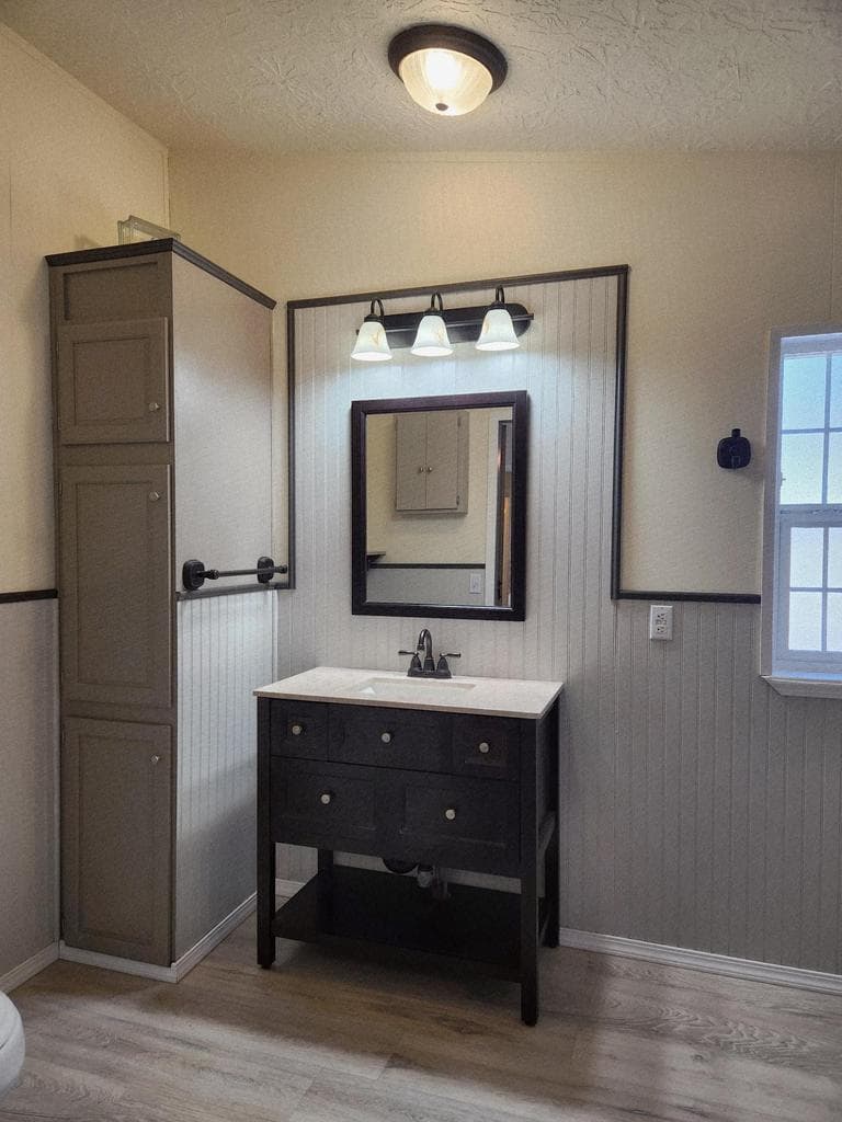Primary suite has wainscoting, decorative vanity and mirror, lots of storage.