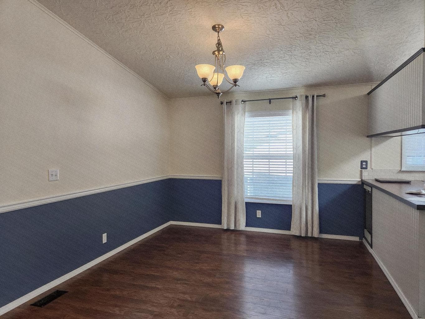 Nice dining room with chandelier, drapes and blinds.
