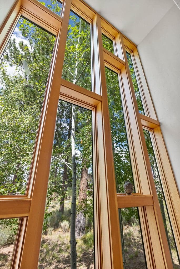 Floor-to-ceiling wall of windows overlooking the treetops. A stunning architectural feature leading upstairs.