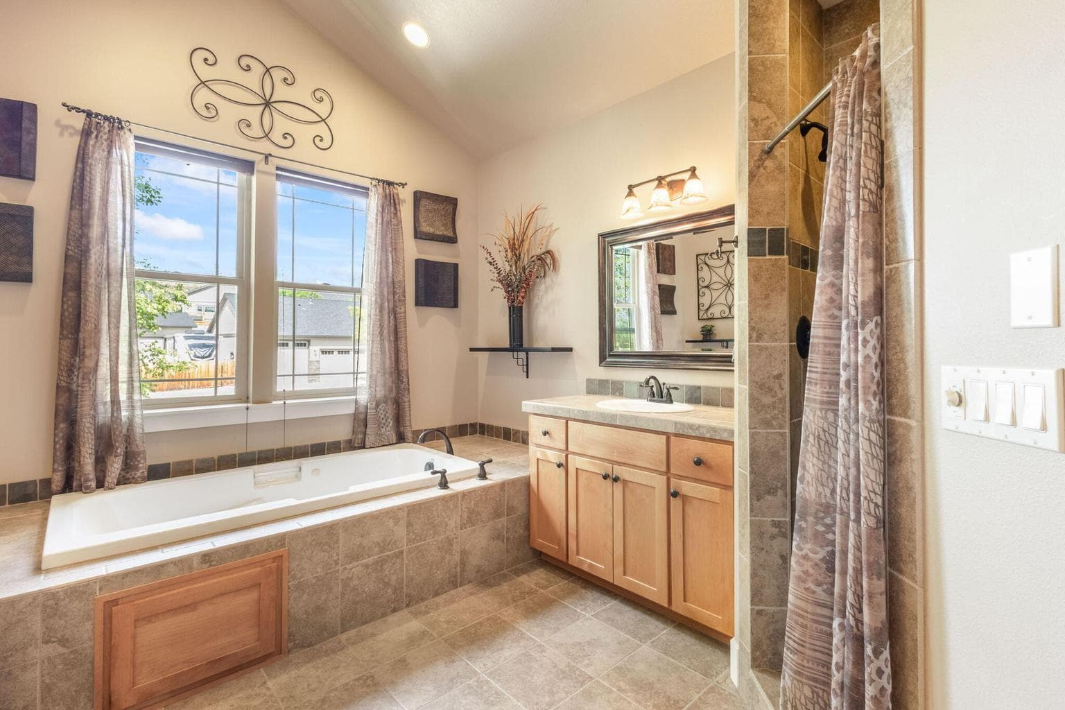 Primary bathroom with jetted tub, double vanity sinks in separate spaces, tiled shower.