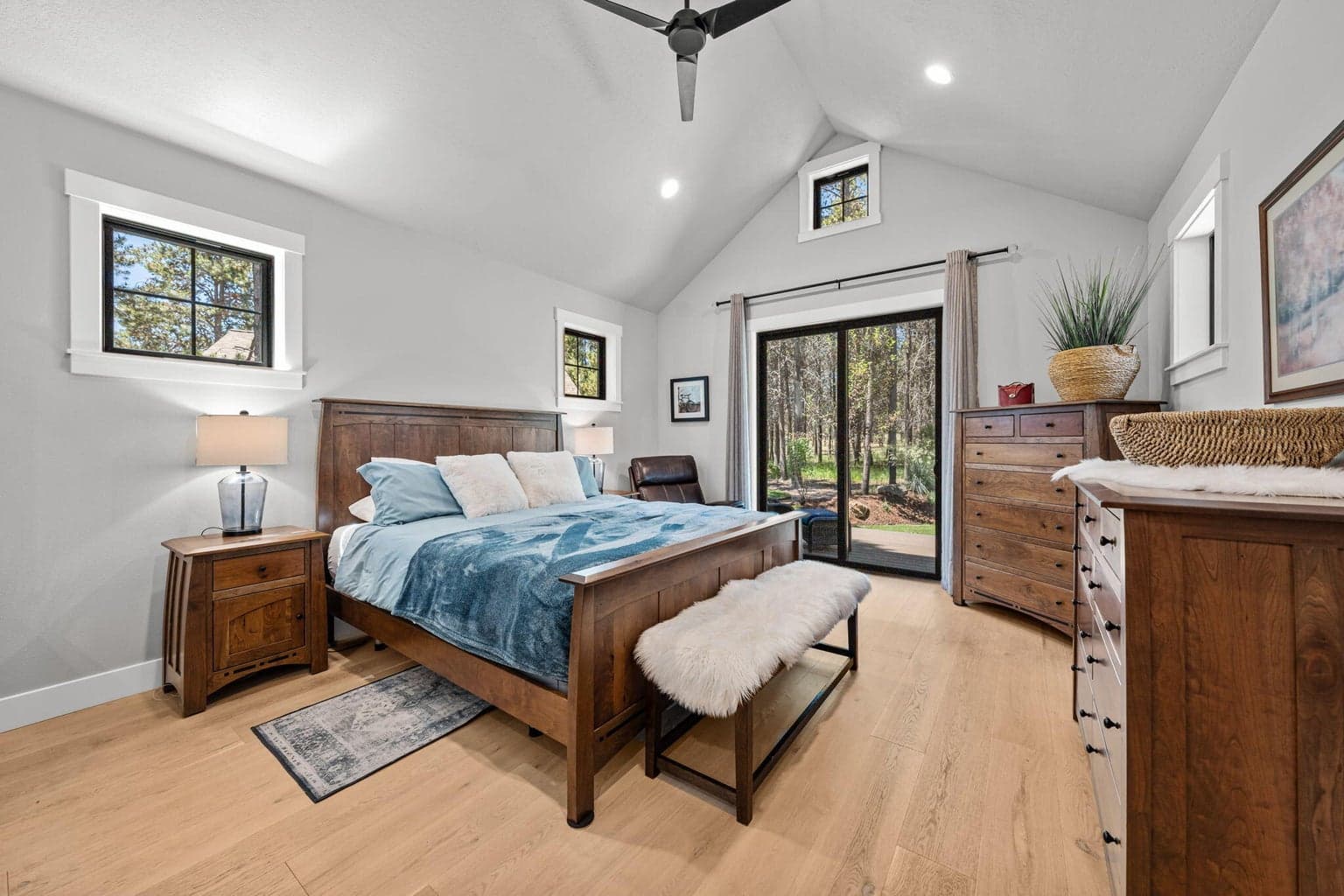 Vaulted primary bedroom with ceiling fan and sliders to deck.
