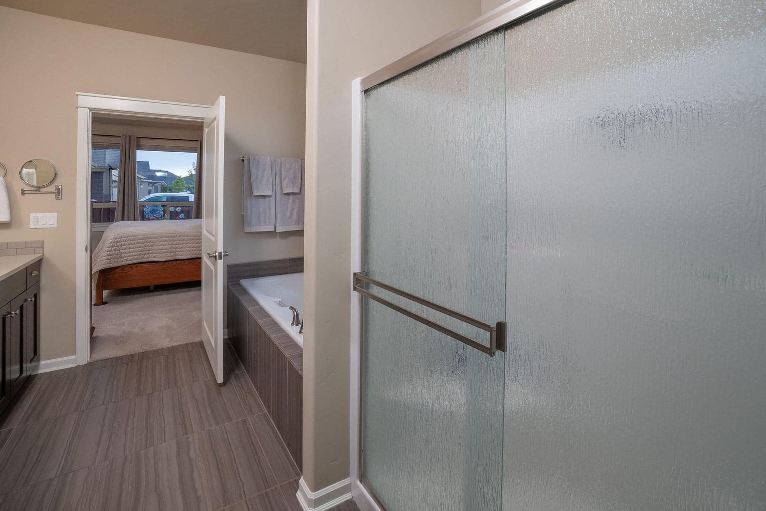 Primary suite bath with built-in soaking tub, tile surround and flooring.