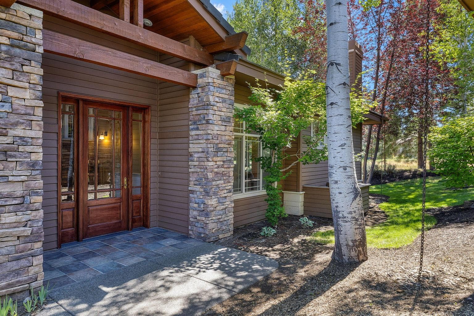 This highly sought-after floorplan features a welcoming walkway leading to an impressive entry framed by stacked stone columns and a soaring gabled roof.