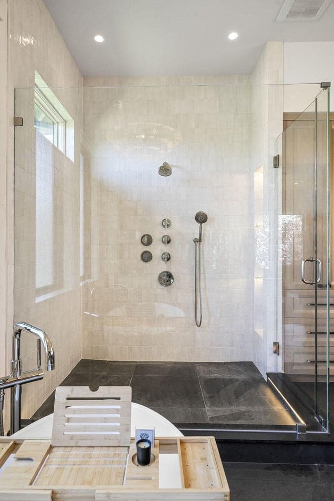 Glass enclosed spa-like shower with multiple shower heads, built in lighted shelves, and lighted floor.