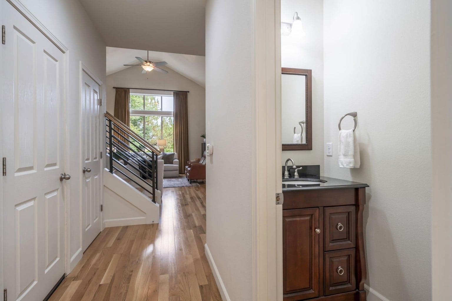 You can see the beauty of the floors in this long run from the entry to family room in back. The floor to ceiling drapes really elevate the space! You can see the main floor 1/2 bath and the door that leads to the garage.