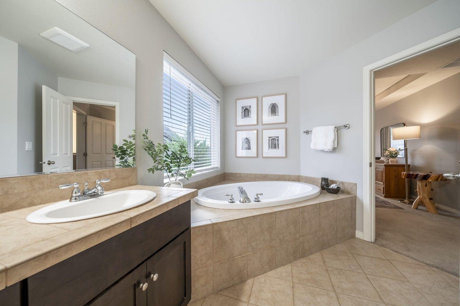 The primary bath has a tile floor and countertop, dual vanities, a 2 person soaking tub, and a separate room with a tiled walk-in shower. There are newer vent fans in both spaces.
