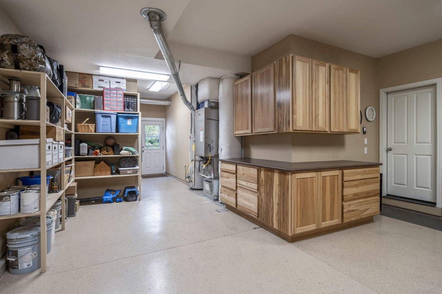 The 2 car garage has an epoxy coating on the floor, built-in wood shelves, hickory cabinets with soft close drawers, the furnace and water heater, and a 5 x 10 locking hobby room. The man door leads to the back yard,