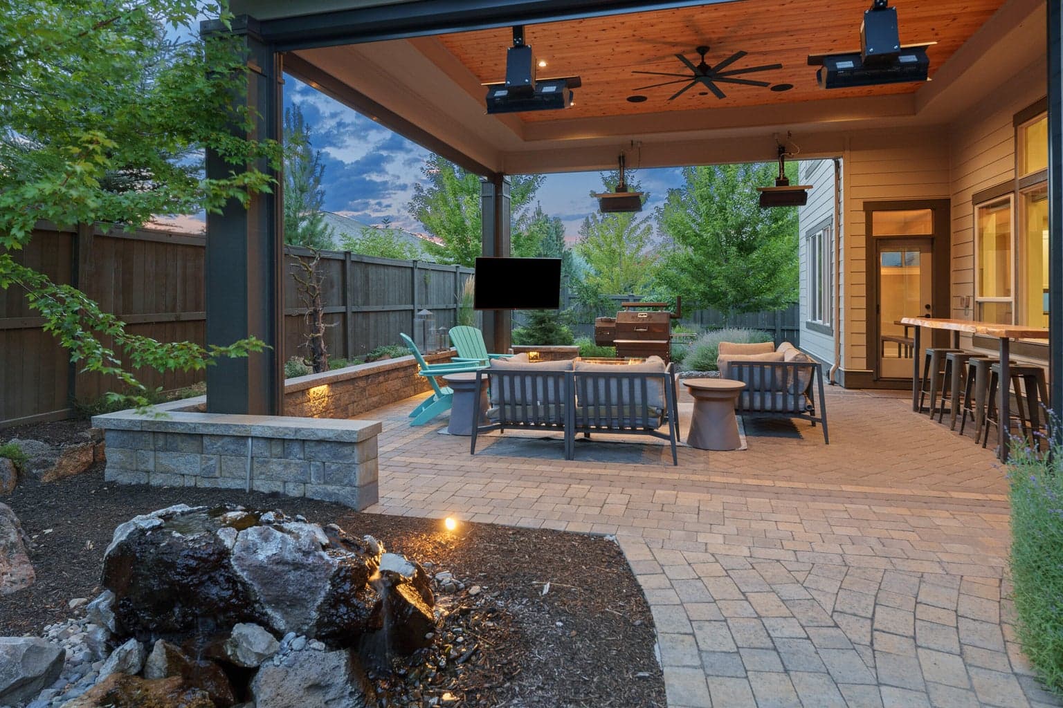 Four season outdoor living space with ceiling-mounted heaters and automated privacy screens