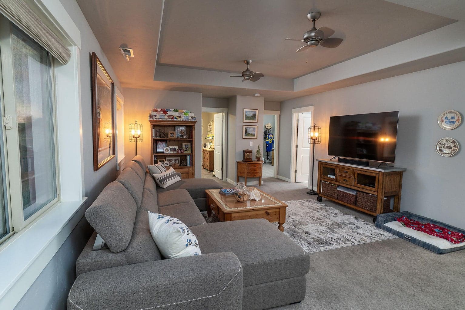 Loft living area with coffered ceiling and ceiling fans. View to the rear of home.