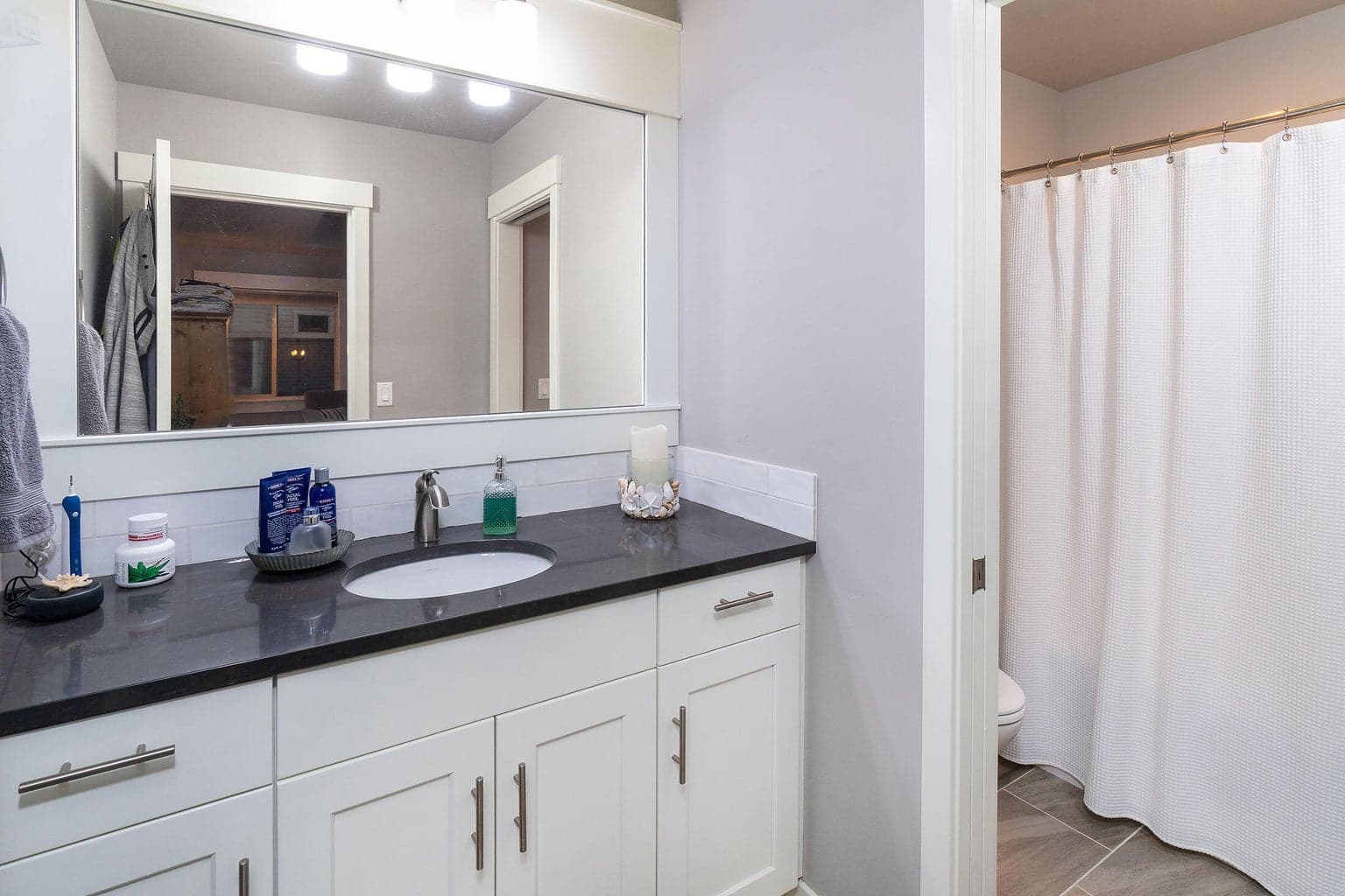 Guest bath has tile floors and wood-wrapped mirror