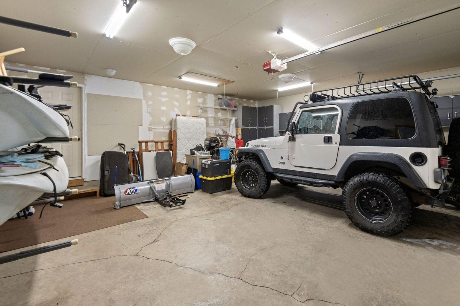 Interior of the oversized 2 -car garage- plenty of storage room in addition to two cars. Door to the guest quarters is beyond the kayaks.