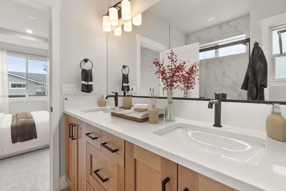 Primary bath with quartz countertops, dual vanity, and tile shower. This photo has been virtually staged.