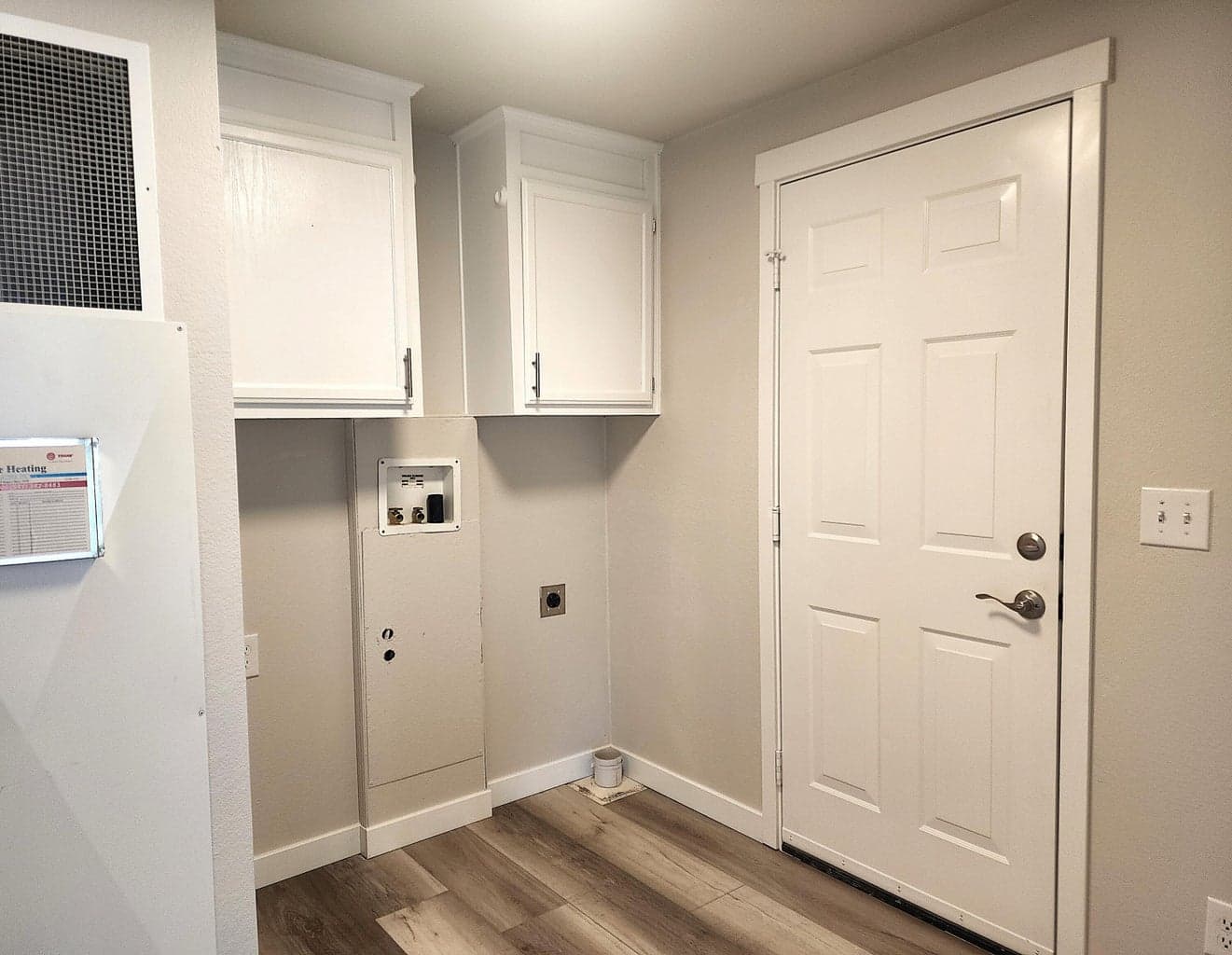 Laundry room with overhead cabinetry and door leading to double garage