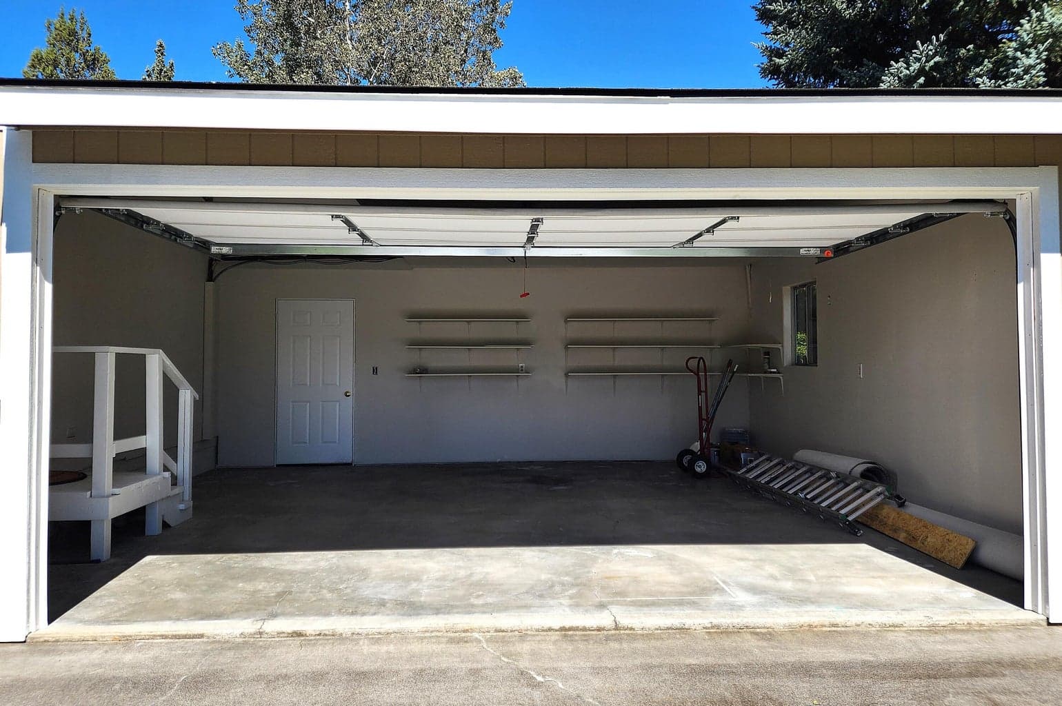 Double garage with shelving and door to backyard