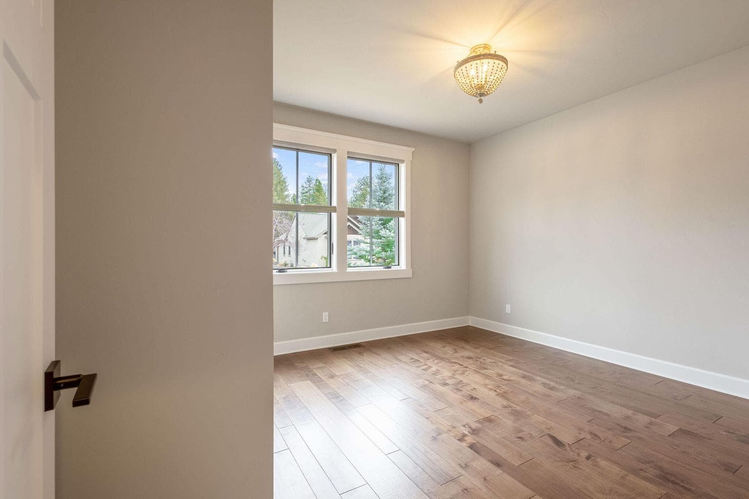 Lower level guest bedroom with hardwood floor and an abundance of natural light.