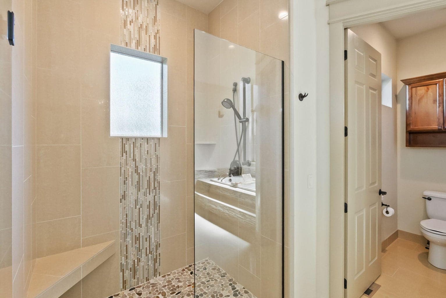 Walk in tile shower and 1 of 2 enclosed toilets